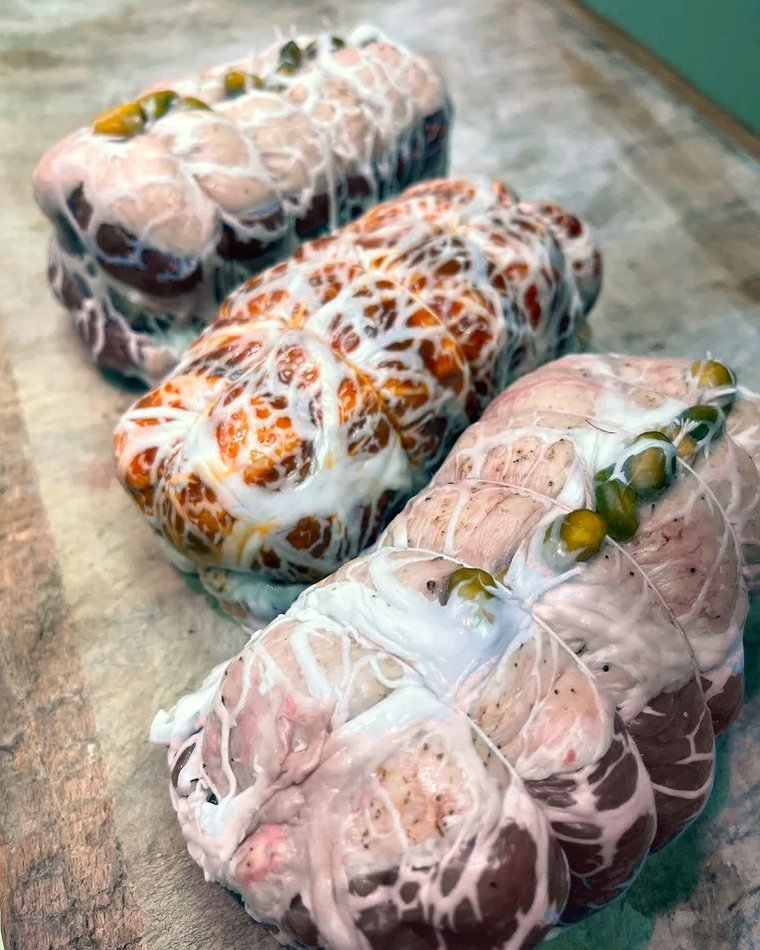 Rôtis de porc farcis et ficelés, alignés sur le billot